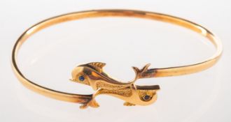 A dolphin torque bangle, designed with two dolphins, each set with a circular-cut sapphire eye,