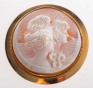 A large cameo brooch, depicting a group of three females with a scenic background,