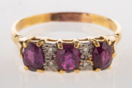 A ruby and diamond ring, set with three oval cut rubies,