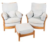A pair of light oak and upholstered armchairs by Ercol, modern; each with slatted backs and sides,