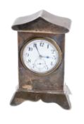 A miniature silver mantel clock having a