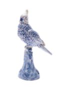 A faience figure of a cockatoo, modelled perching on a stump and with painted blue decoration,