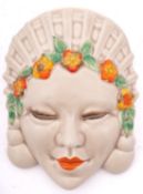 A Clarice Cliff 'Marlene' mask wall pocket wearing an elaborate headdress and floral band to her