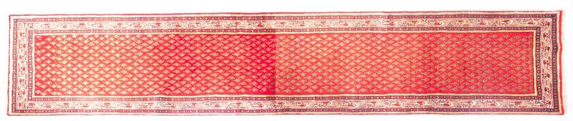 A Malayer runner, the tomato red field with an all over design of lozenge motifs,