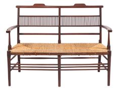 An Edwardian stained beech love seat, the twin chair back with spindle upright panels,