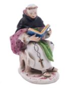 A Bow figure of a seated monk reading from the Holy Bible held in both hands,
