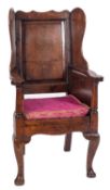 An early 18th Century oak Wainscot armchair, the fielded panel wing back with shaped cresting rail,