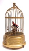 A German gilt metal caged singing bird automaton, 20th century; the articulated bird with feathers,