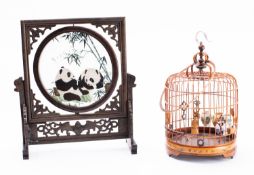 A Chinese table screen and a bamboo bird cage the carved wood screen with glass and silk