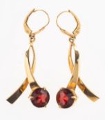 A pair of garnet set drop earrings, of crossover design and each set with a circular-cut garnet,