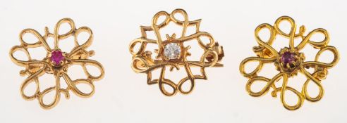A group of three similar brooches, a group of three similar openwork flowerhead designed brooches,
