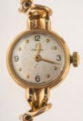 Omega a lady's gold wristwatch the round silvered dial having raised dot and Arabic numerals,