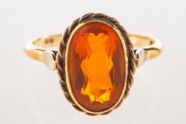 A 9ct gold ring, bezel and rope twist set with an oval-cut orange stone, UK hallmark, size Q1/2, 3.