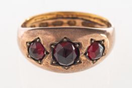 An antique garnet ring, set with three faceted garnets in an enclosed back setting,