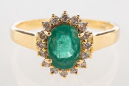 An emerald and diamond cluster ring, claw set to the centre with an oval-cut emerald,