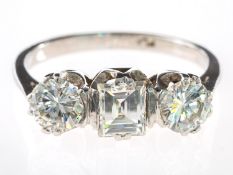 An impressive three stone diamond ring, claw set to the centre with a rectangular-cut diamond,