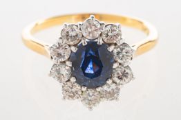 A sapphire and diamond cluster ring, set to the centre with an inky blue oval-cut sapphire,
