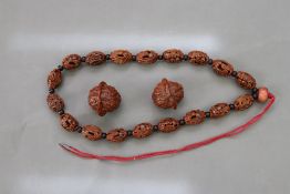 A Chinese Carved Nut Rosary; and Two Walnuts