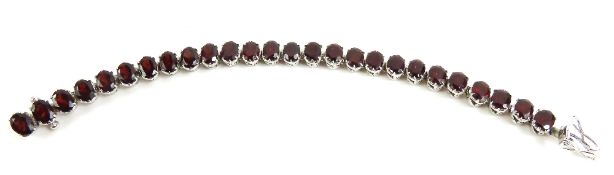 A garnet set bracelet, each oval facetted garnet s