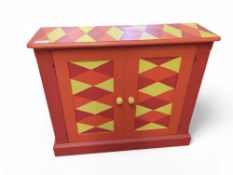 A pine two door cupboard, painted in red, orange a