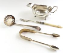 A silver sauce boat, with capped handle, and on th