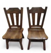 A pair of stained oak chairs with block supports