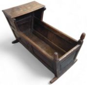 A 20th century stained oak crib/cradle with panell