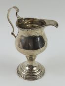 A tall silver cream jug with beaded rim and base a