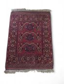 A small wool rug of predominantly red shades, but