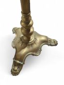 A brass lamp upon decorative base with three feet.