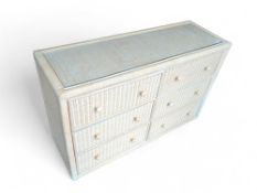 A modern, white-dusted and rattan chest of drawers