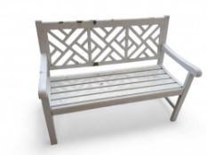 A metal garden bench painted white, with three sym