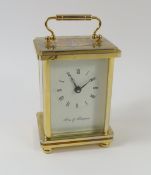A gold-coloured carriage clock with swing handle a
