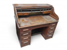 A 20th-century oak roll-top desk with plinth base,