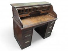 A 20th-century oak roll-top desk on outer casters