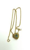 A heart shaped locket set with turquoise and a rub