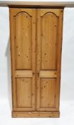 20th century pine two-door wardrobe opening to reveal an adjustable shelf and clothes rail, one door