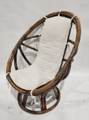 20th century bamboo swivel rocking chair with single upholstered cushion, raised on a circular base,