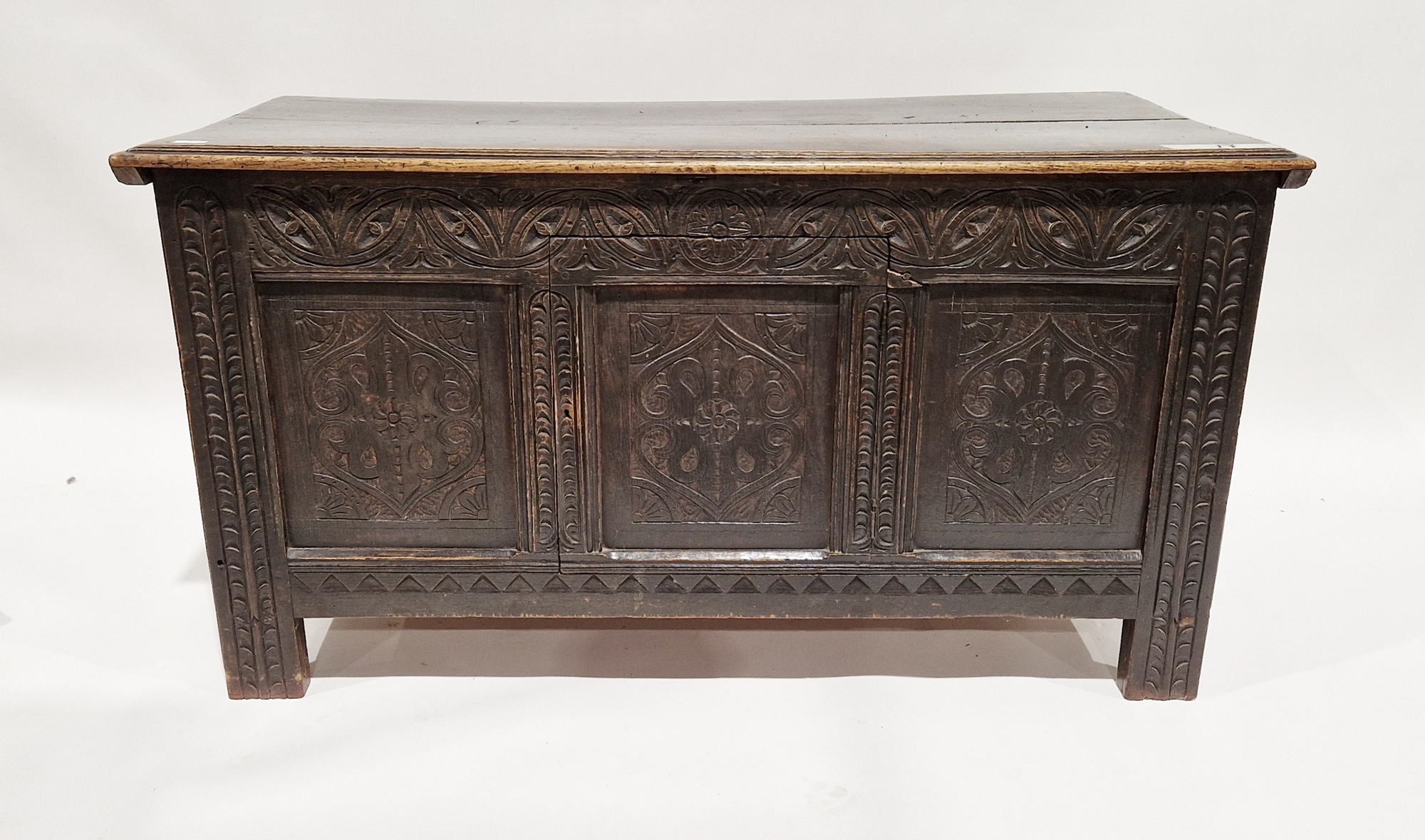 Antique oak coffer, the planked top with lunette frieze, the three-framed panel front scroll