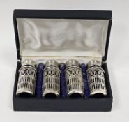 A set of four silver plated pepperettes, on a pierced lattice decoration, blue glass liners, in
