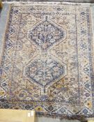 Eastern wool rug of caucasian design with two stepped octagonal blue medallions to the madder field,