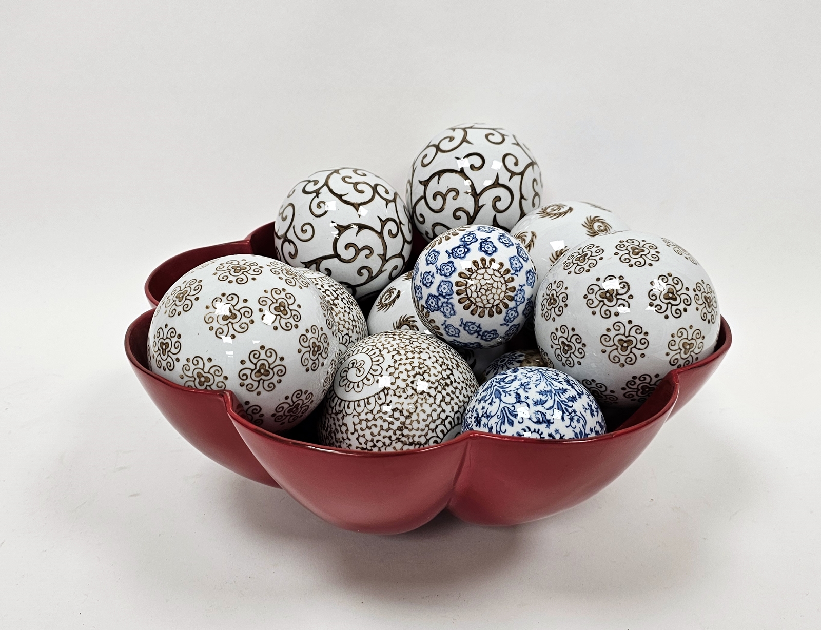 Quantity of printed ceramic spheres with scroll and stylised floral decoration in red lacquered bowl