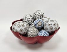 Quantity of printed ceramic spheres with scroll and stylised floral decoration in red lacquered bowl