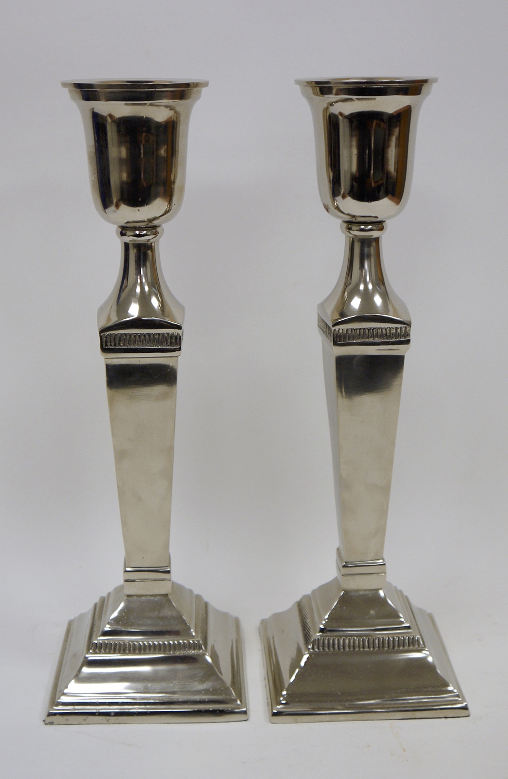 Pair of Covent Garden Trading Company white metal urn-shaped column candlesticks, each surmounting a