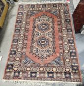 Pakistani apricot ground wool rug with central geometric medallion enclosing two hexagonal shapes,