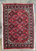 Hand knotted Iranian rug, red background with symbols in green, mustard, cream and light blue