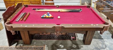 Pool table with burgundy felt playing surface, wooden-effect frame and leather ball pockets and
