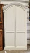 20th century wardrobe, the arched top opening to two panel doors with a hanging rail and three