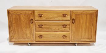 Ercol pale blonde elm windsor sideboard comprising a central bank of three drawers flanked by