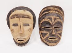 Two large African carved wooden tribal masks, circa 1940s, each with carved features and apertures